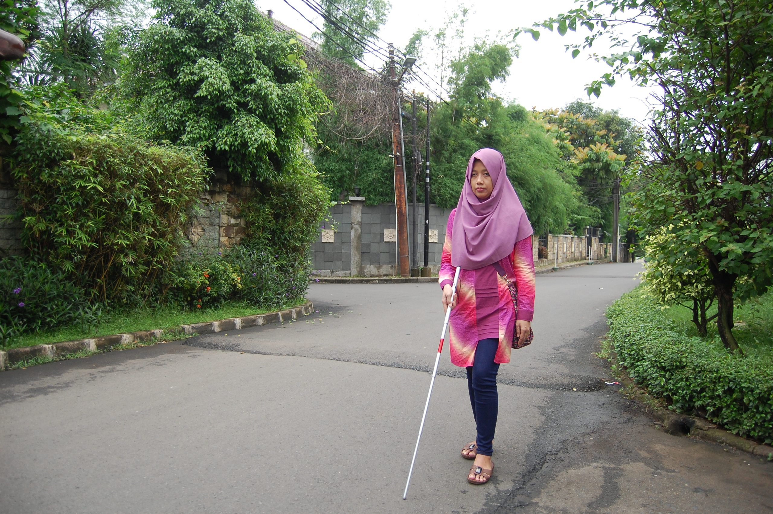 tunanetra berjalan sendirian dengan tongkatnya. Background suasana perumahan