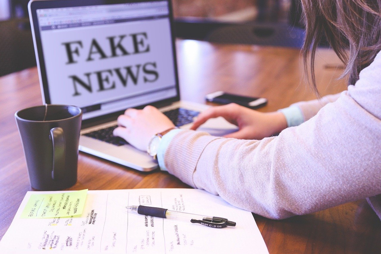 seseorang di depan laptop dengan layar bertuliskan fake news