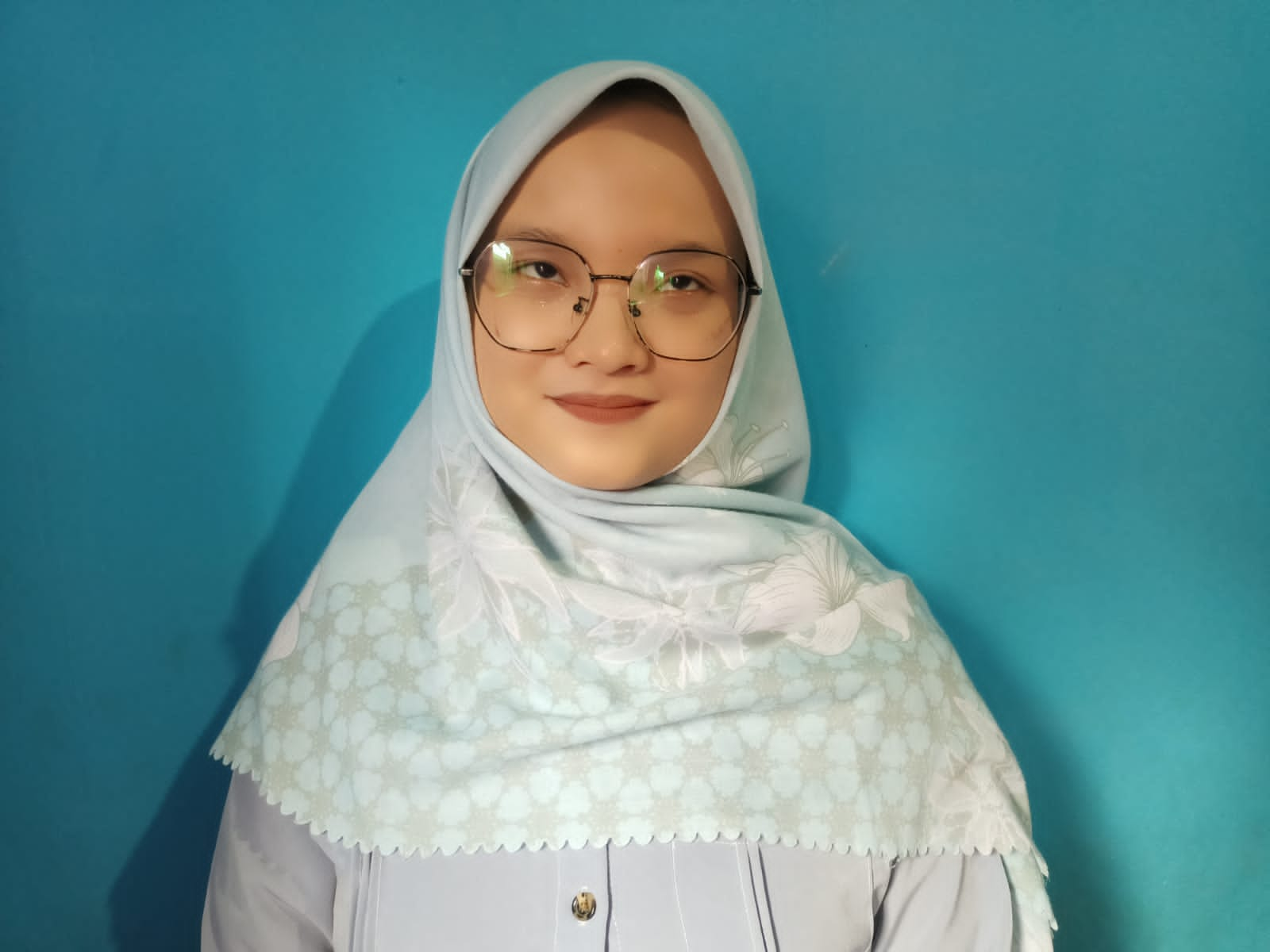 foto Ayu Ningsih menggunakan hijab putih dengan background biru