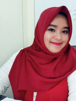 Stella Putri mengenakan hijab merah tersenyum ke arah kamera