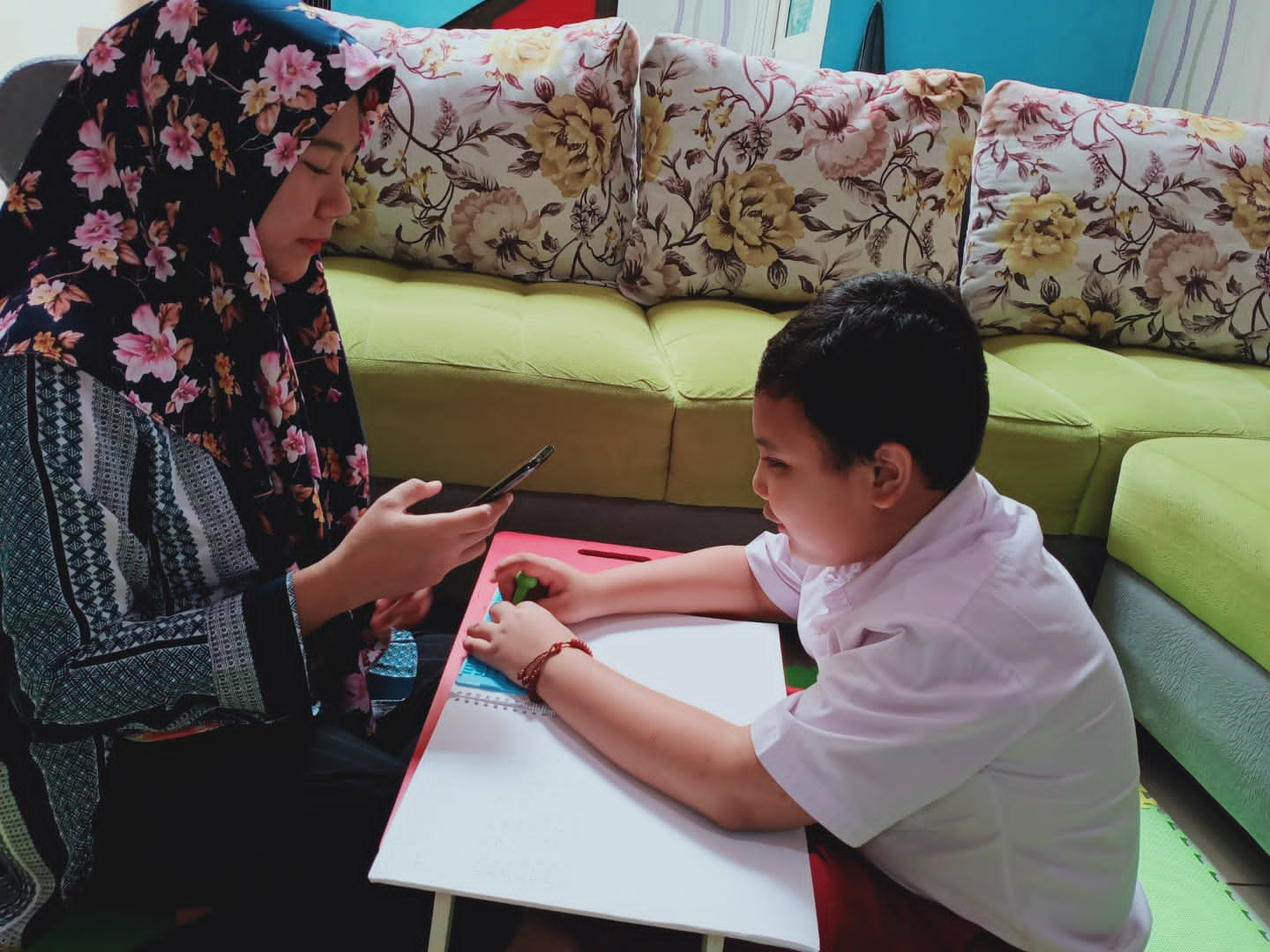 Rakha sedang belajar dengan buku Braille, di hadapannya ada ibundanya yang mendampingi