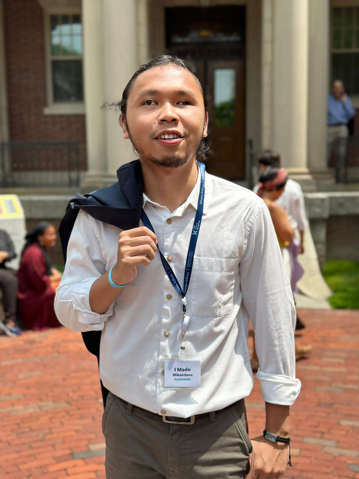 Wikan mengenakan kemeja putih dan blazer di depan gedung Universitas Harvard, Amerika Serikat